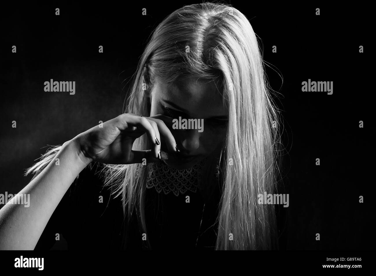 sad woman crying on black background, monochrome Stock Photo