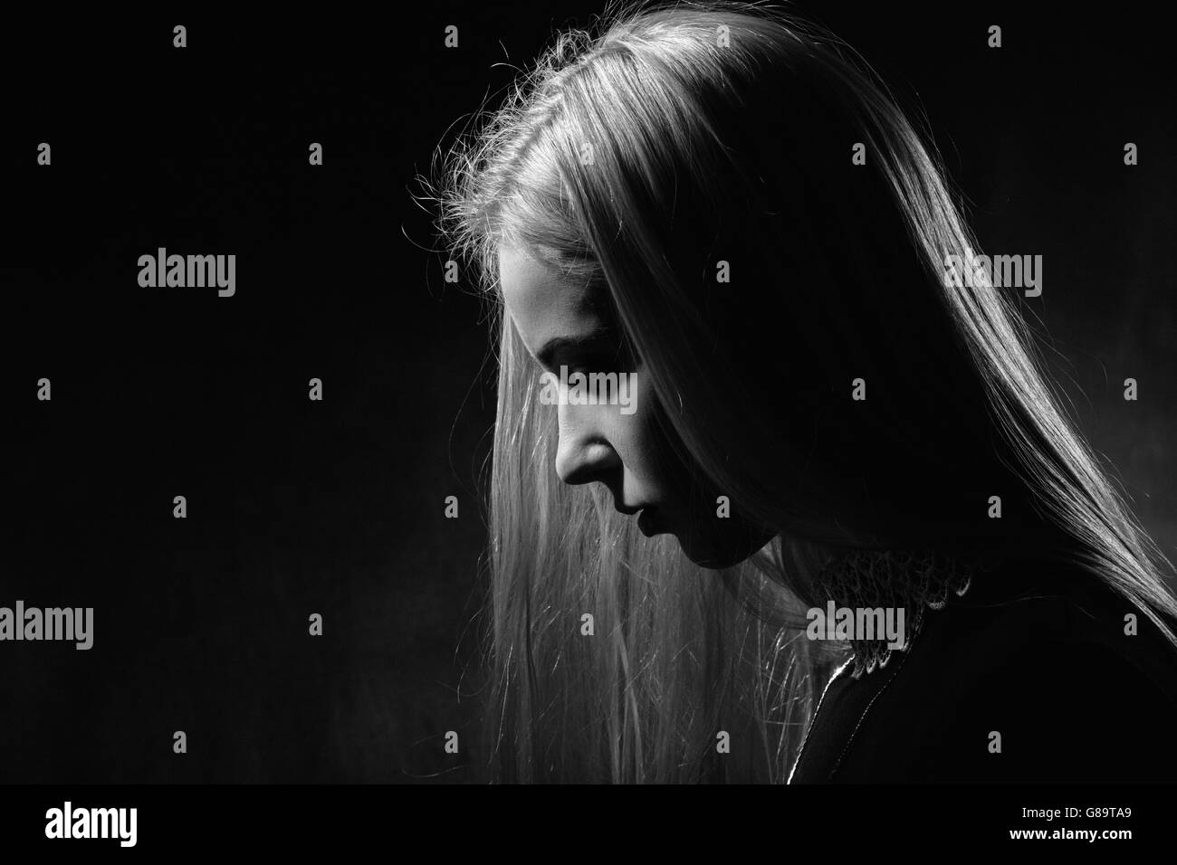sad pensive girl profile on black background, monochrome image Stock Photo