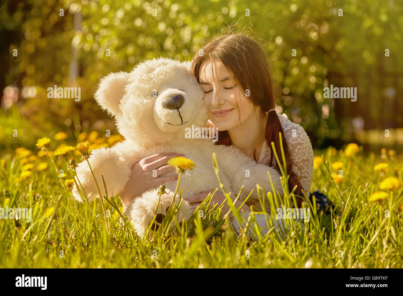 girl with teddy bear lying on dandelion meadow Stock Photo - Alamy