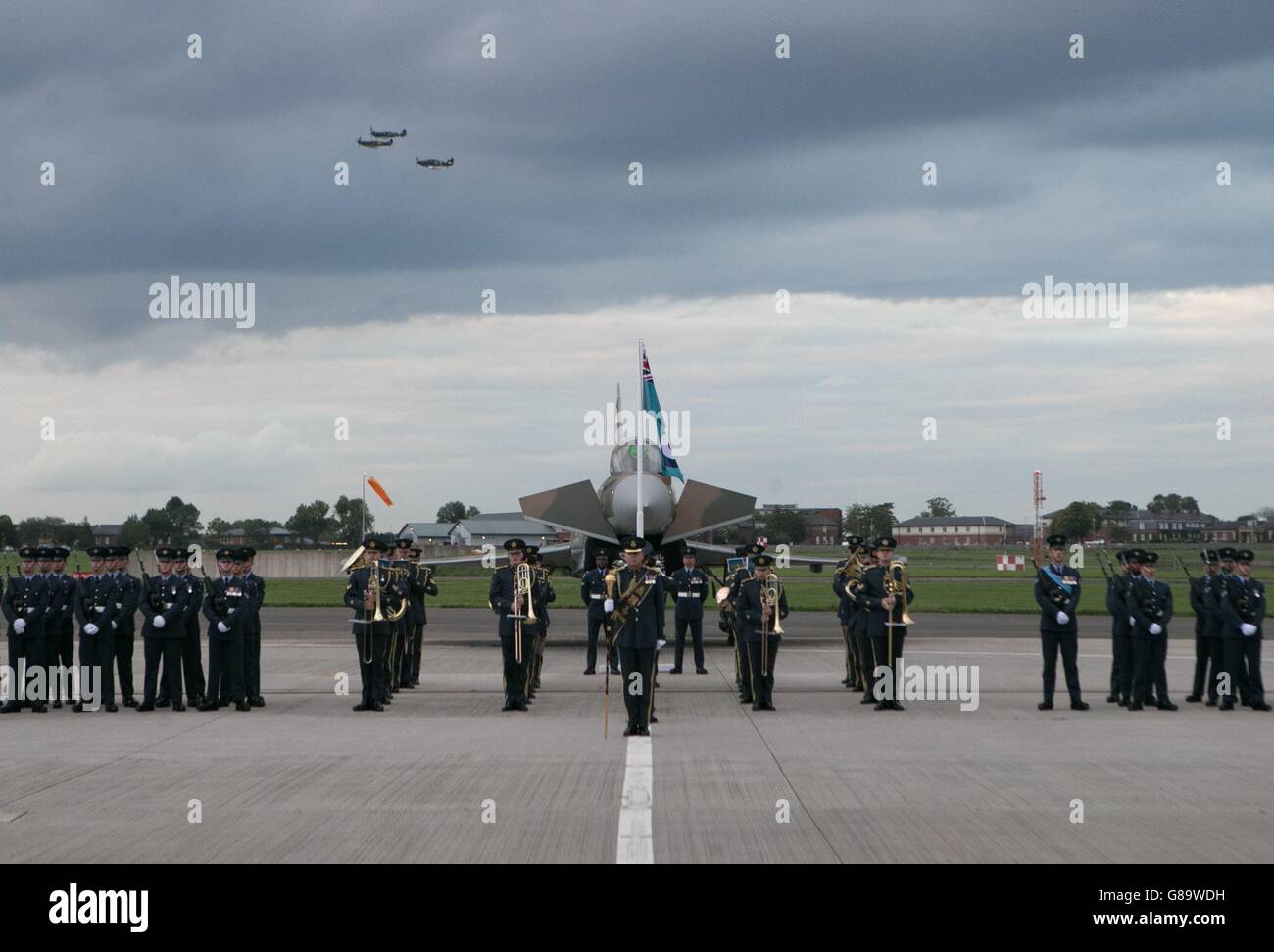 The Central Band of the RAF and and the Queen's Colour Squadron take part in a ceremony on the tarmac at RAF Northolt as planes including a Hurricane and a Spitfire perform a flypast during the RAF Benevolent Fund's commemorative dinner to mark the 75th anniversary of the Battle of Britain. Stock Photo