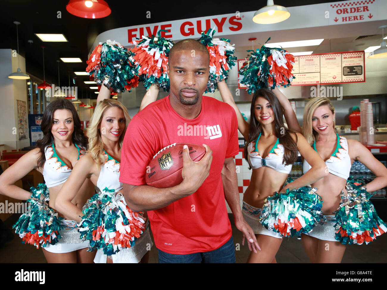 EDITORIAL USE ONLY The Miami Dolphin Cheerleaders Etta, Dancia, Britt and Paige and UK NFL Ambassador Osi Umenyiora, dual Super Bowl winner who recently retired from the game, celebrate the launch of the NFL and Five Guys partnership at the burger restaurant in Covent Garden, London. Stock Photo