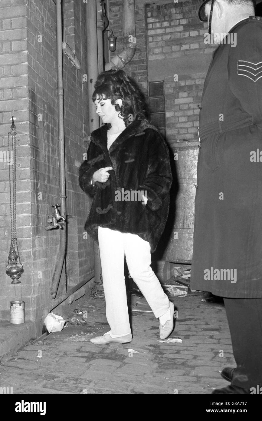 Actress Elizabeth Taylor slips in through the stage door of the Playhouse Theatre in Oxford, where she was appearing with husband Richard Burton in the Oxford University Dramatic Society production of Marlowe's Dr Faustus. She was playing the non-speaking role of Helen of Troy, who only appears in the second half. When the play ended last night, the cast took 15 curtain calls and enjoyed over nine minutes of applause. Stock Photo