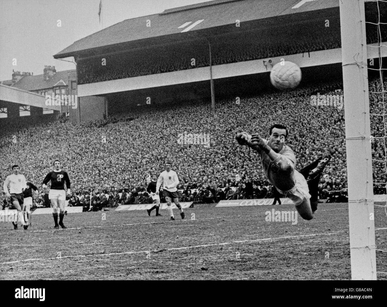 Scotland goalkeeper Ronnie Simpson's frantic dive fails to save this shot from Martin Peters (extreme left), who scored for England in the 1-1 draw at Hampden Park, Glasgow. Stock Photo