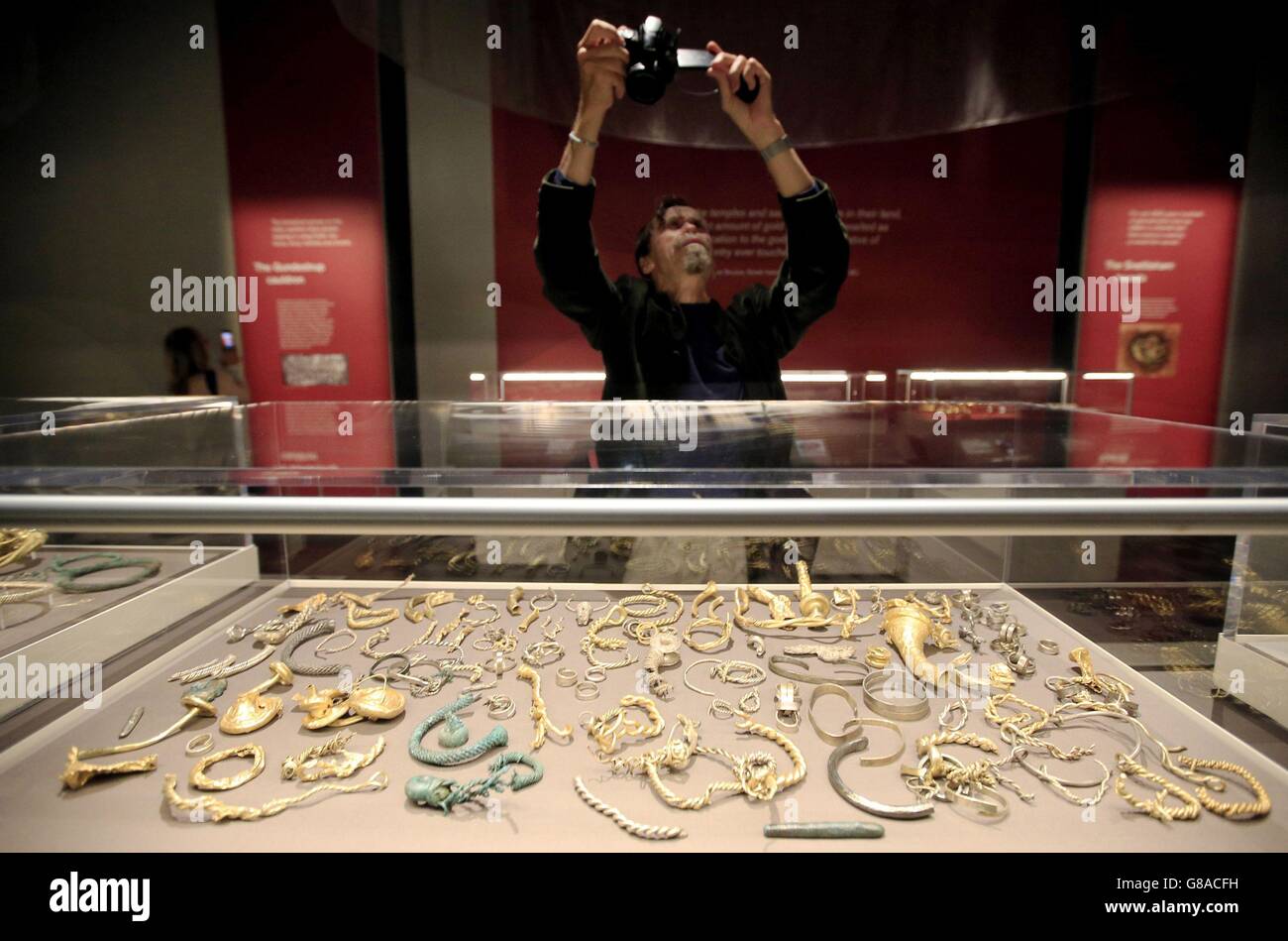 A visitor photographs alloys of gold, silver, and copper, part of the Snettisham Hoard, on display during a press view of the exhibition, Celts: art and identity at the British Museum, London. Stock Photo