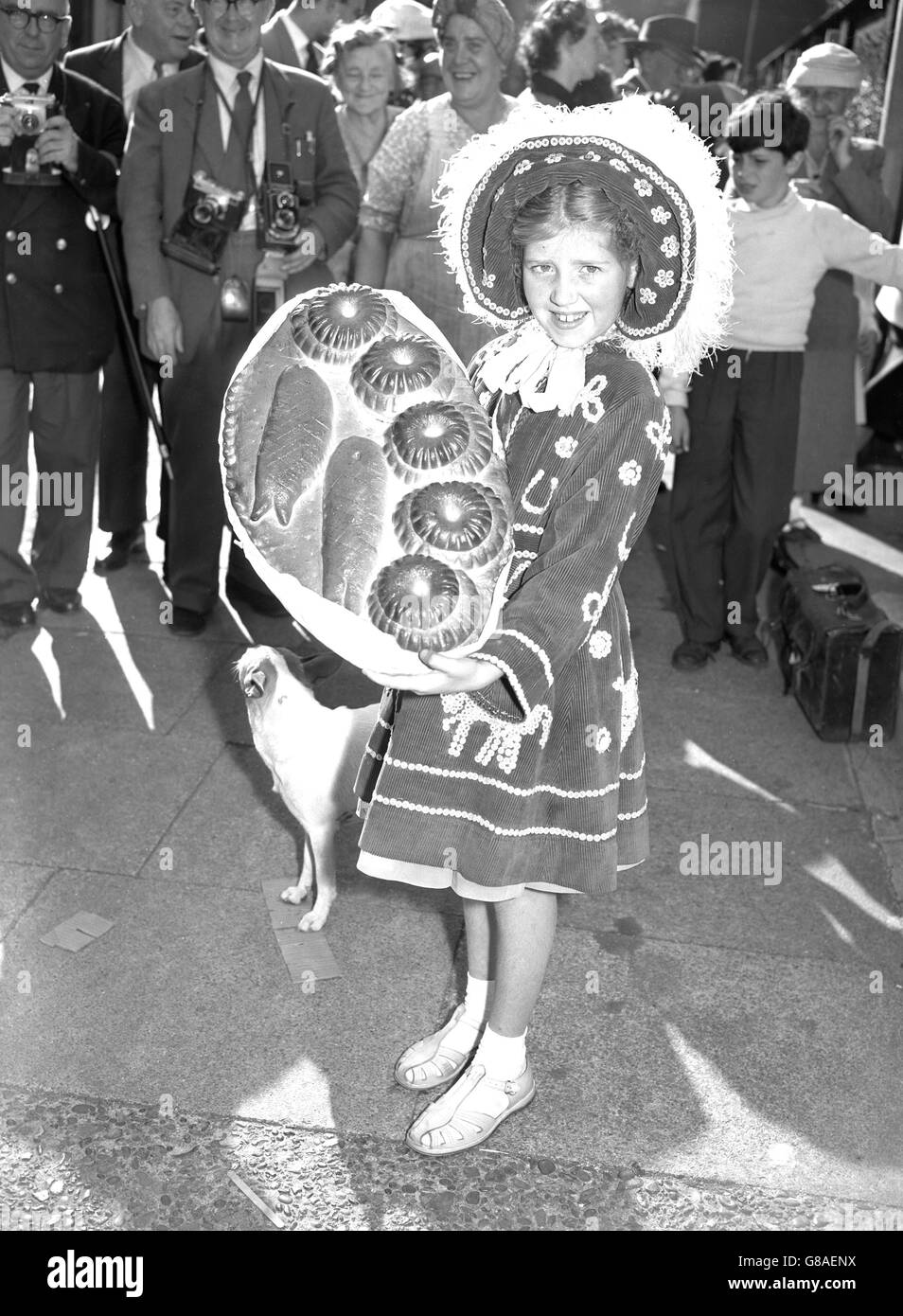 Pearly Princess Shirley Ashmith, 10, of Stone, Kent, carries a bread loaf patterned with five loaves and two fish, on her way to Lady Margaret Church, Walworth, where the annual Harvest Festival was being held. The procession into church of the Pearlies is watched every year by visitors from all over the world. Stock Photo