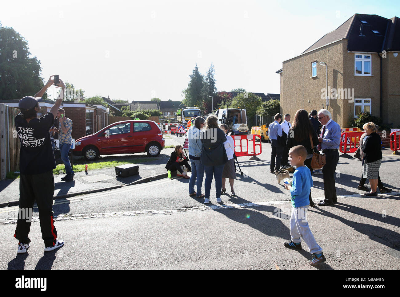 Residents try and get a closer look at a sinkhole which has opened up on a residential street in St Albans. Stock Photo