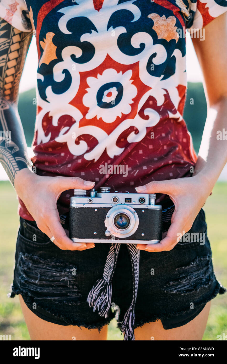 Woman with tattoo holding vintage camera Stock Photo