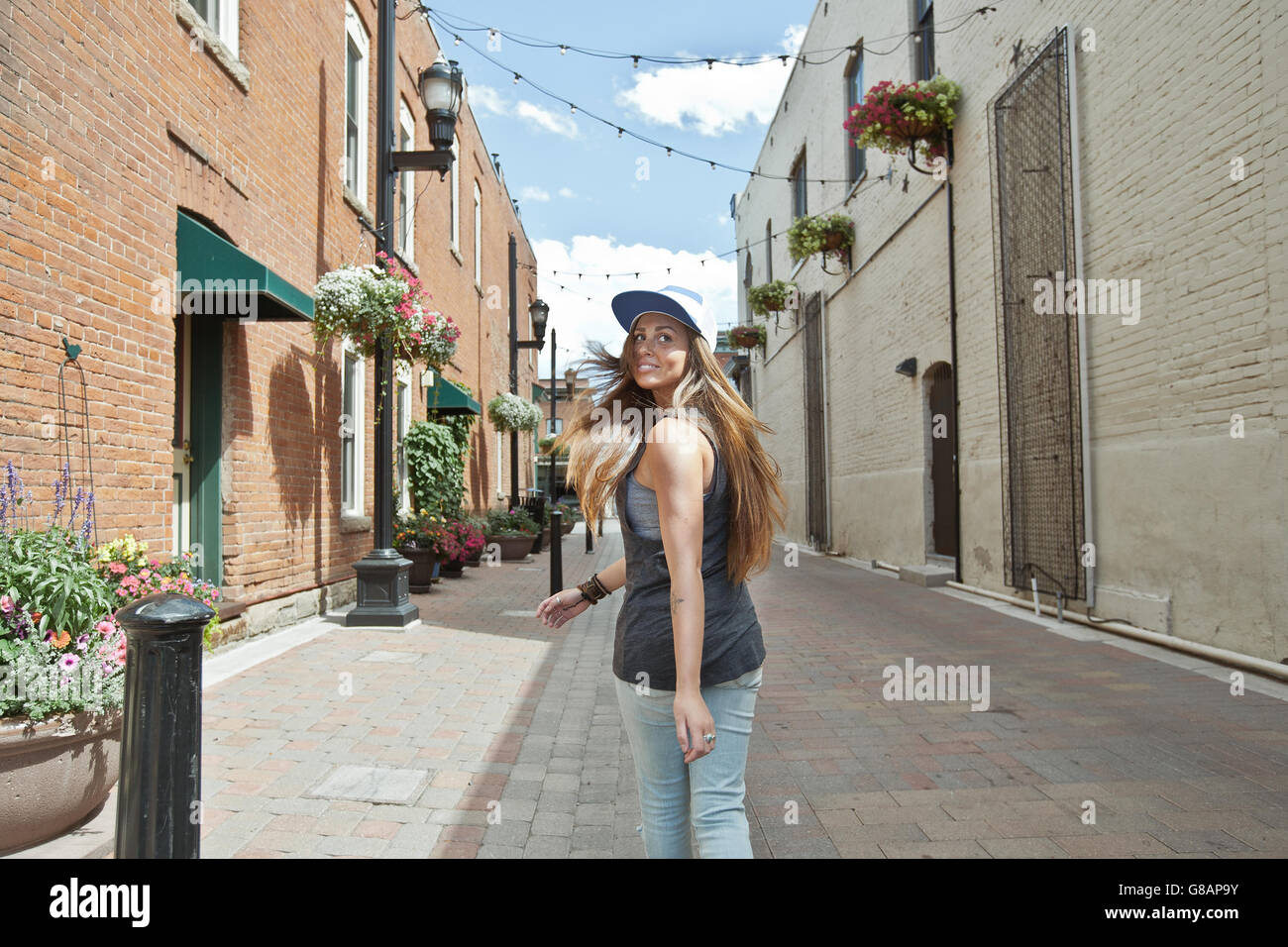 Young woman running down alley looking over shoulder, Colorado, United States Stock Photo