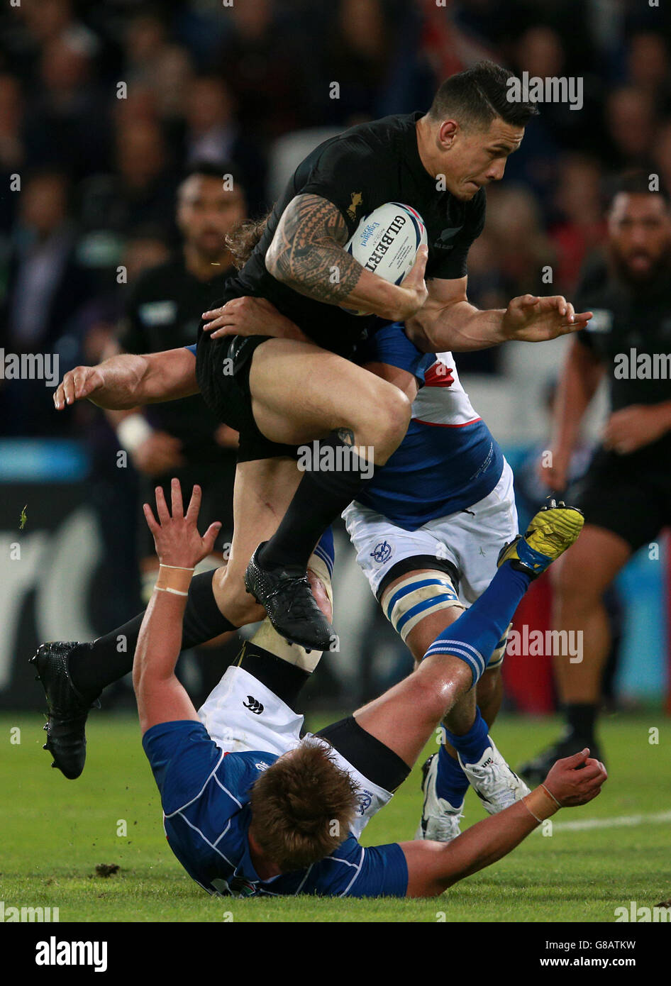 New Zealand's Sonny Bill Williams (centre) drives at the line as he is tackled by Namibia's Torsten van Jaarsveld (below) and Jacques Burger (right) during the Rugby World Cup match at the Olympic Stadium, London. Stock Photo