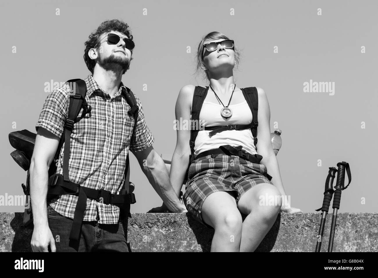 Two young people tourists hiking by sea ocean water. Backpackers couple on summer vacation trip journey. Stock Photo