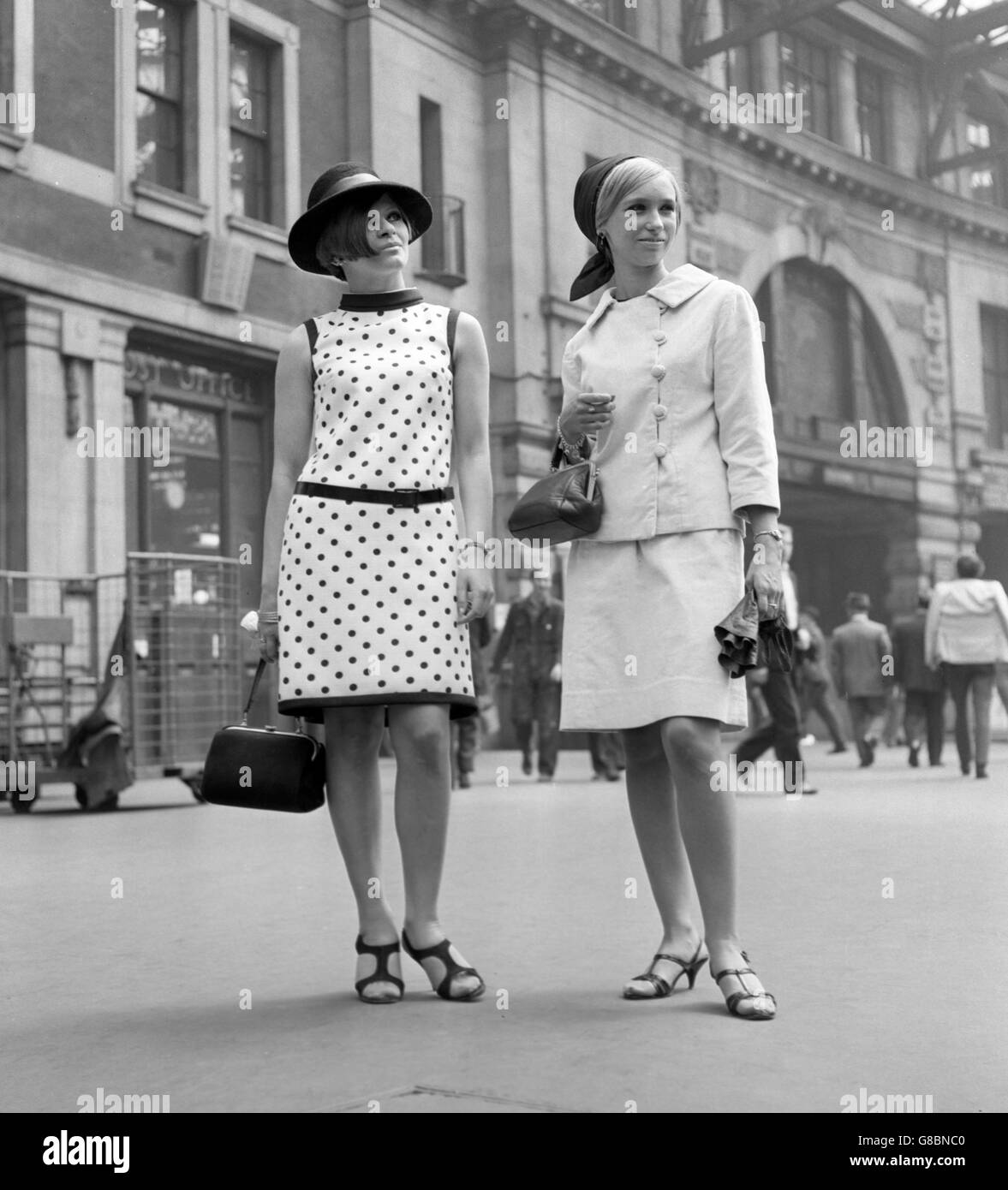 (l-r) Eliane Barthus, 20, wearing a black Spanish-style hat with a polka dot dress, and Jean Storer, 21, in a pastel blue velvet suit and headscarf, leave Waterloo Station in London for the second day of the Royal Ascot race meeting. Stock Photo