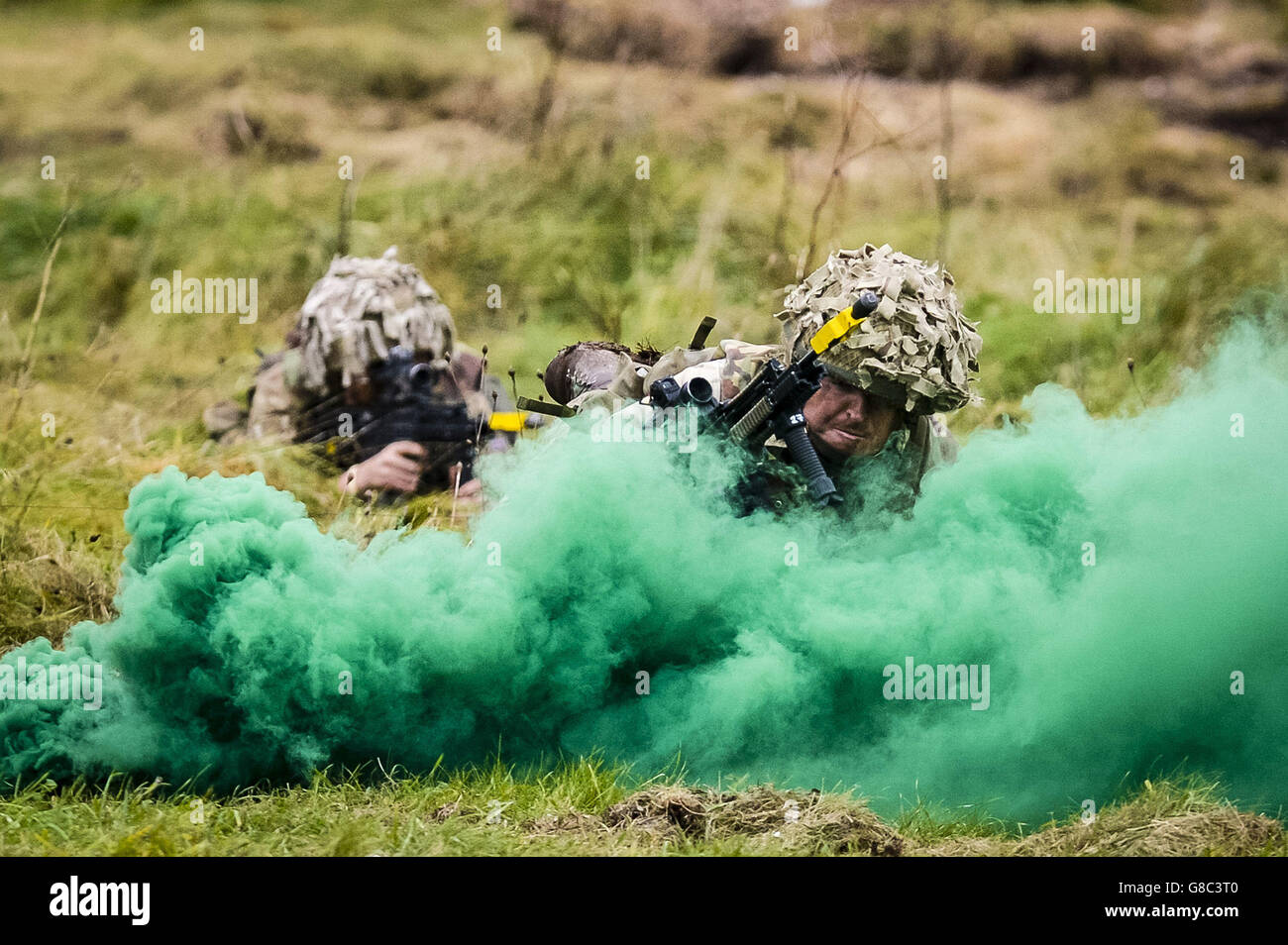 British Army soldiers crawl through smoke as they attack and move forward, supported by armour, during a Combined Arms Manoeuvre Demonstration on Salisbury Plain, Wiltshire. Stock Photo