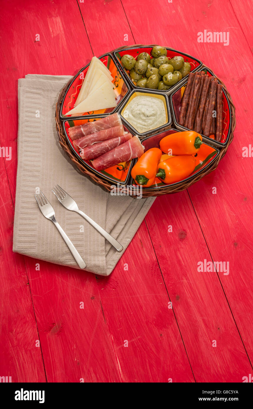 Basket with Spanish tapas on a rustic red wooden table Stock Photo - Alamy
