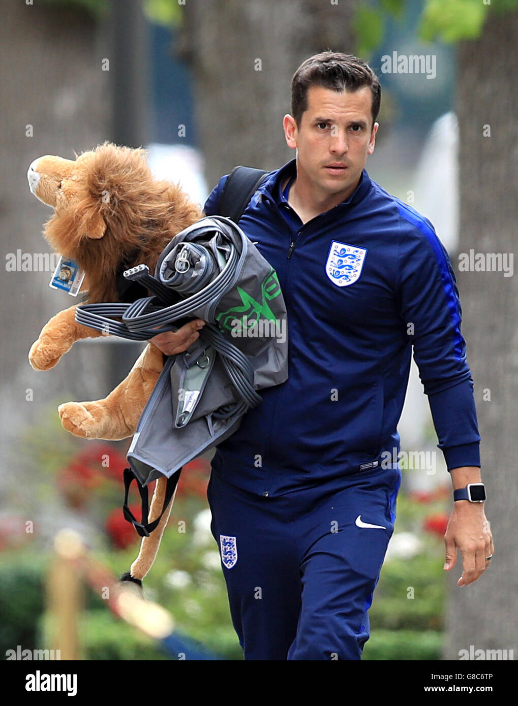 England elite physiotherapist Steve Kemp carrying mascot Leo the Lion as he arrives at the team hotel in Chantilly, France. England were knocked out at the round of 16 stage of the 2016 European Championships last night after losing 2-1 to Iceland. Stock Photo