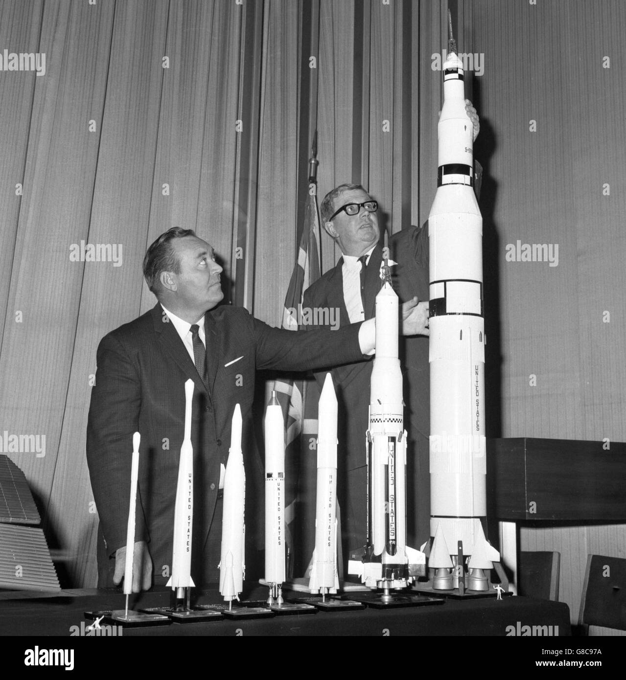 Julian F Rogers (left), a space science lecturer of America's National Aeronautics and Space Administration, with Dr WF Hilton, a member of the Council of the British Interplanetary Society, are pictured at the United States Embassy in Grosvenor Square, London. With them are model rockets from NASA's Spacemobile, a large demonstration van that is to make a three-month tour of British schools and other organisations. Dr Hilton will be one of the lecturers on the tour. Stock Photo