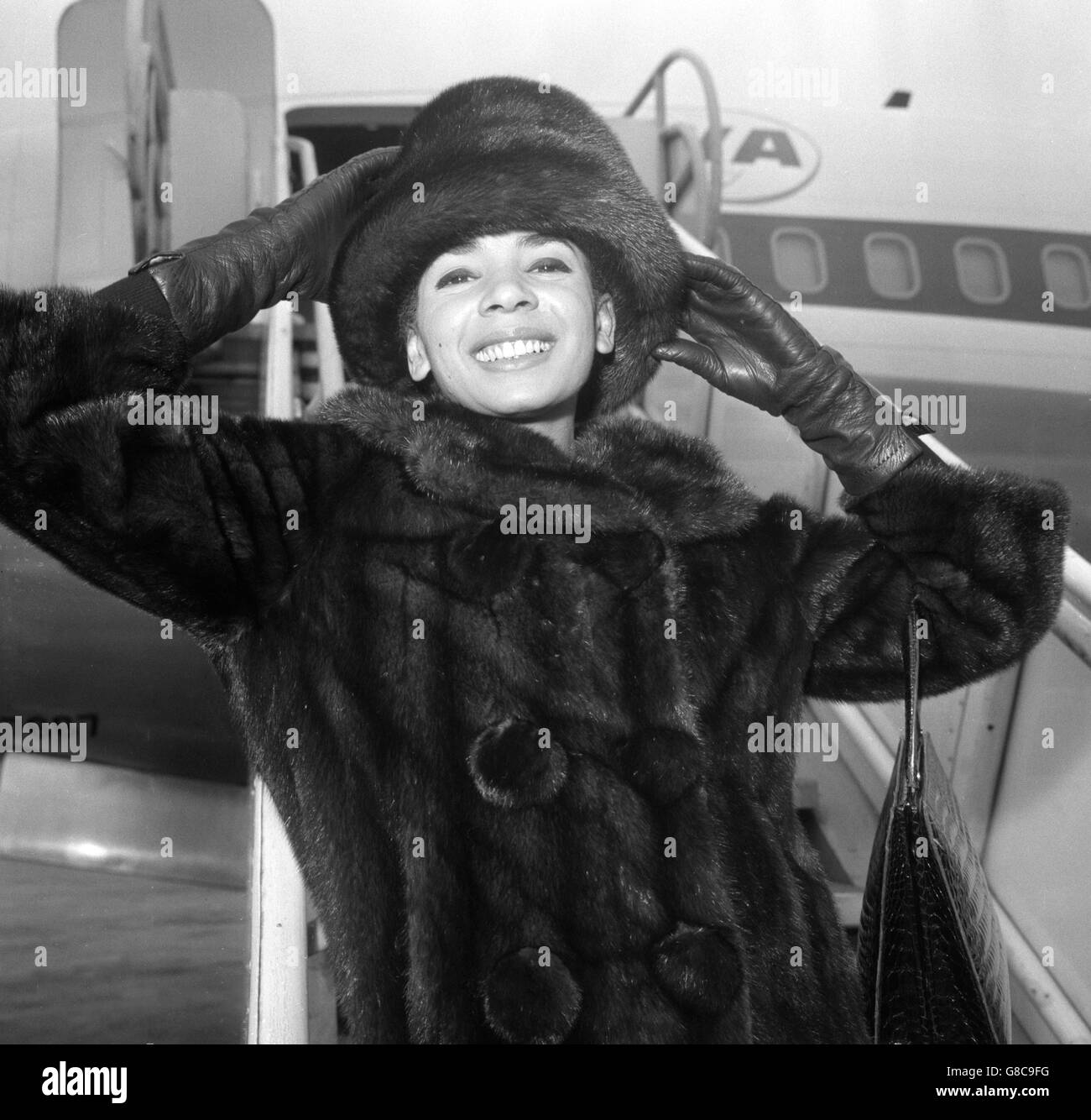 Singer Shirley Bassey is wrapped up warm as she leaves London Airport