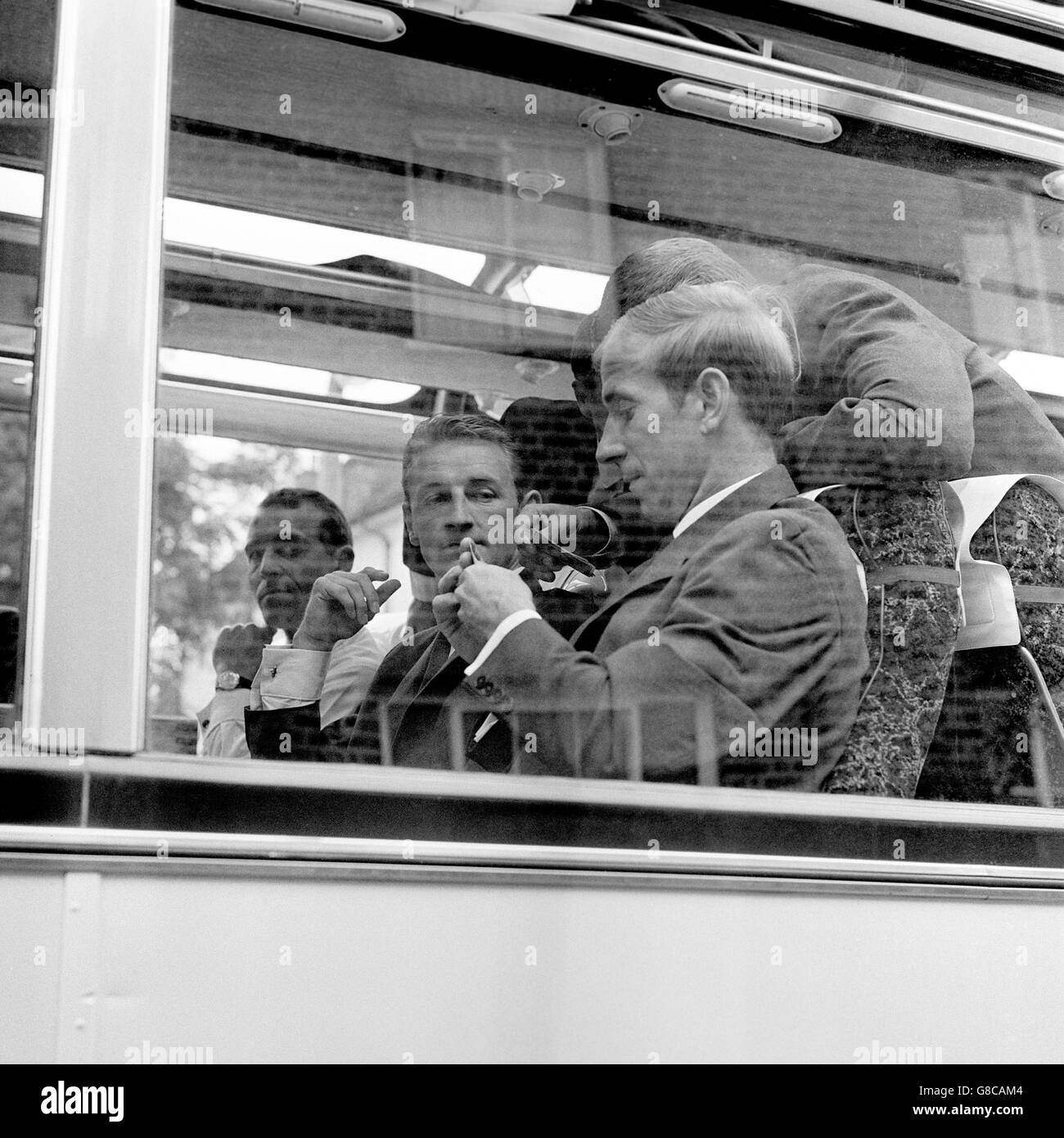 England's Bobby Charlton (third l) studies his cards intently, watched by teammates George Eastham (second l) and Ray Wilson (leaning over), as the players wait to be bussed to Pinewood Studios Stock Photo