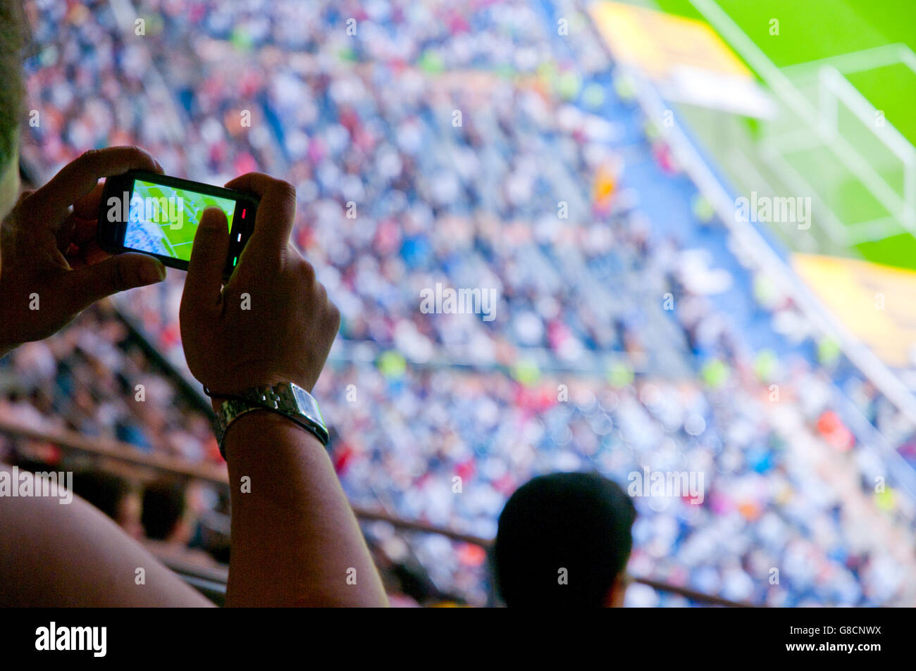Woman taking photos during a football match. Santiago Bernabeu stadium, Madrid, Spain. Stock Photo