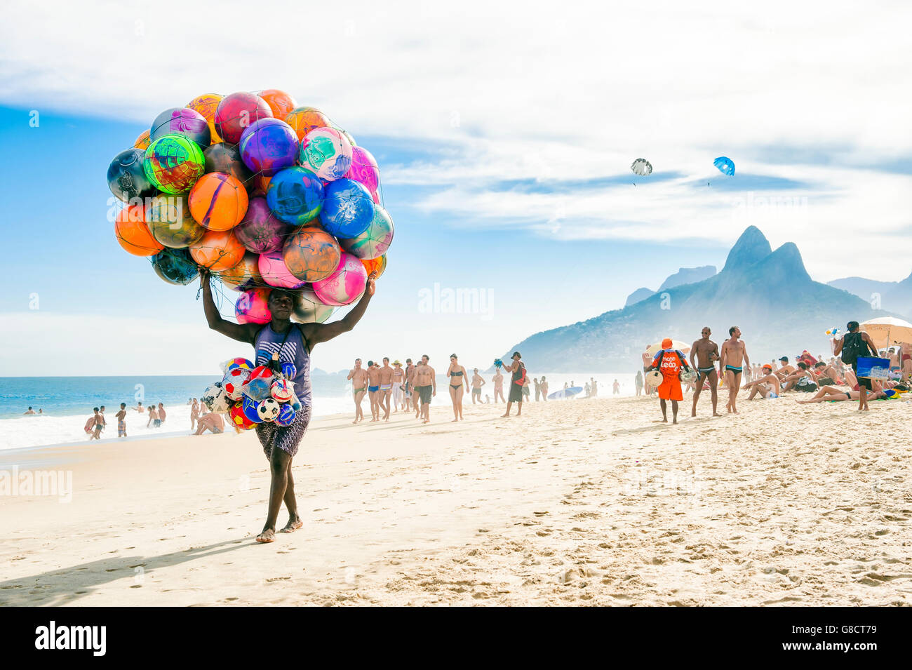 RIO DE JANEIRO - JANUARY 20, 2013: Beach vendor selling colorful beach balls carries his merchandise along Ipanema Beach. Stock Photo