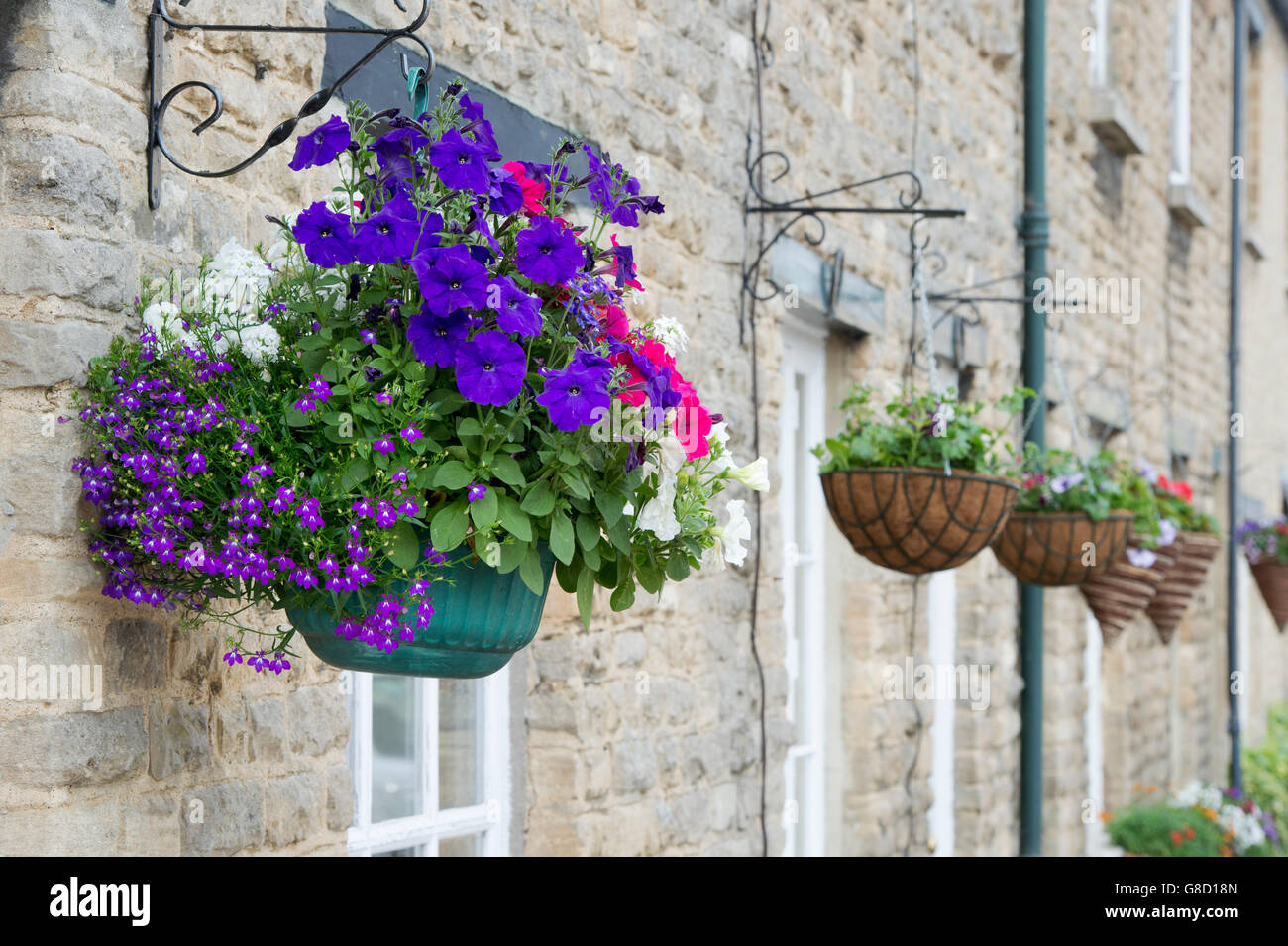 Hanging baskets in front of stone buildings. Bampton, Oxfordshire, England Stock Photo