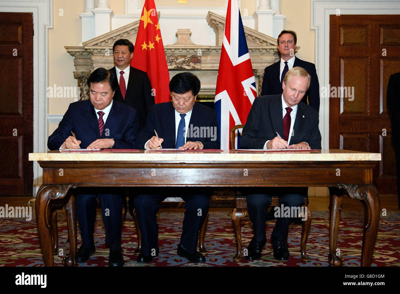 China's President Xi Jinping and Prime Minister David Cameron look on as (seated left to right) Wang Yilin, Chairman of Petro China, Li Quingkui, Chairman of China Huadian Corporation, and Bob Dudley, Chief Executive of BP, sign contracts at the UK-China Business Summit at Mansion House, London, on the second day of Xi's state visit. Stock Photo