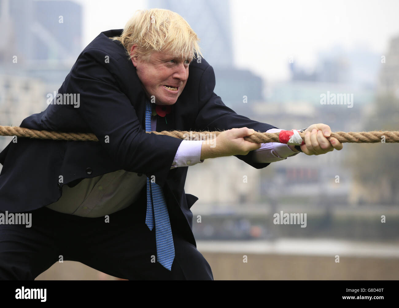 Mayor of London Boris Johnson takes part in a tug of war with personnel from the Royal Navy, the Army and the Royal Air Force at the launch of London Poppy Day, on Potters Field, next to City Hall in London. Stock Photo