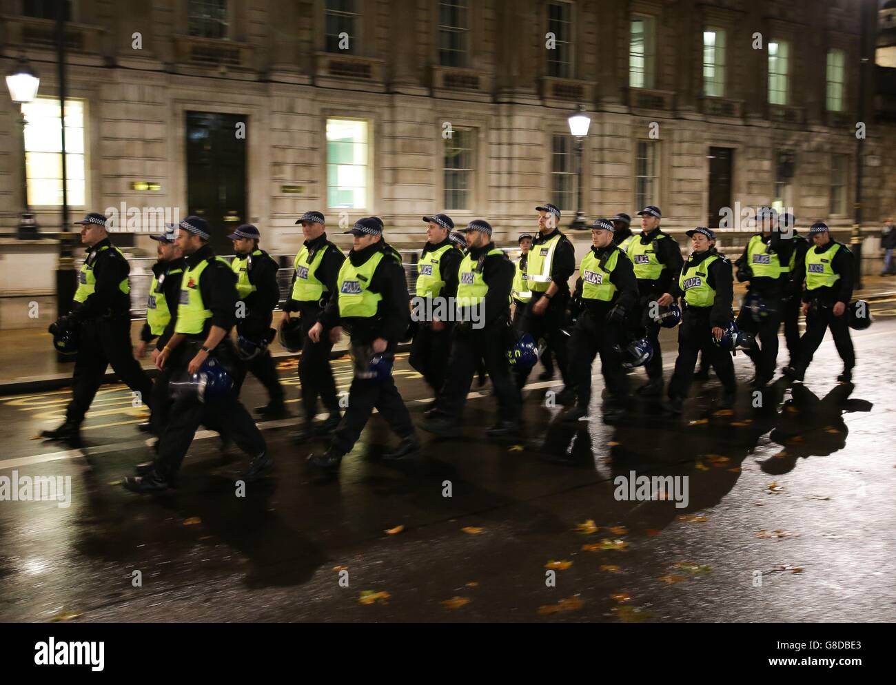 Police officers follow a group of demonstrators at White Hall in London, during the Million Mask March bonfire night protest organised by activist group Anonymous. Stock Photo