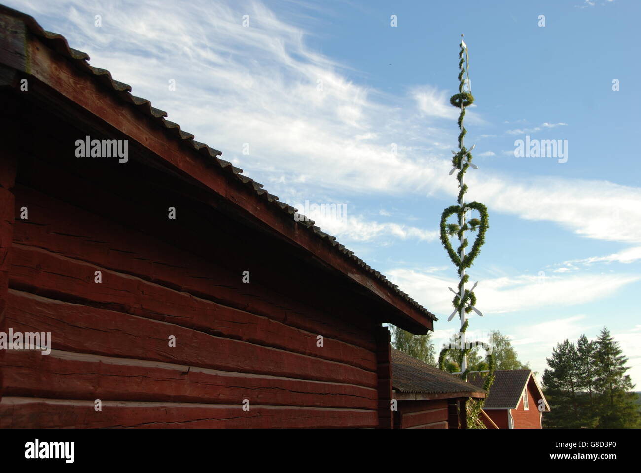 Midsummer pole in Swedish village with traditionally houses painted in red. Stock Photo