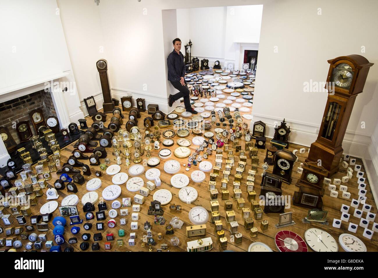 Luke Jerram with his art installation titled 'Harrison's Garden' featuring 1000 clocks in a room at the Thelma Hulbert Gallery in Honiton, Devon. Stock Photo