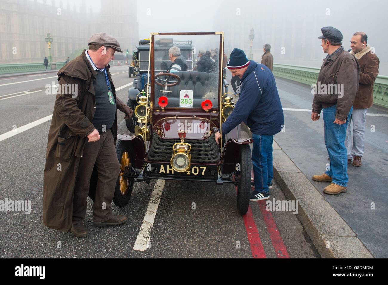 Participants in the Bonhams London to Brighton Veteran Car Run attempt to repair a broken down car on Westminster Bridge, London. Stock Photo