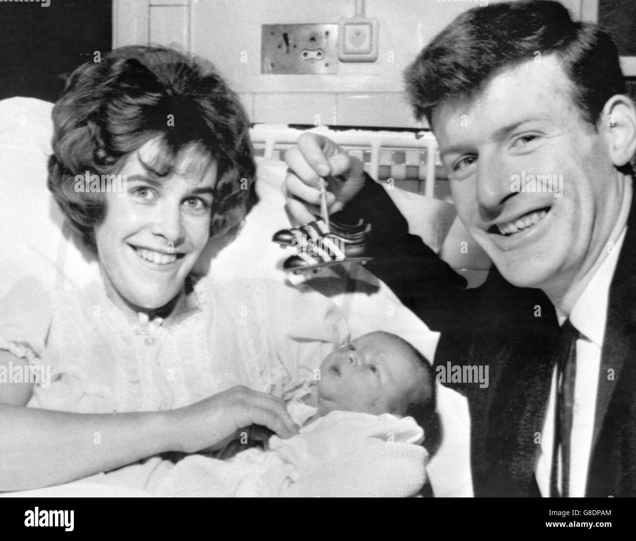 Preston's Scottish full-back George Ross proudly dangles a pair of miniature football boots above his first-born Andrew, in the arms of his mother Pat at the Preston Royal Infirmary. Tomorrow, Preston are at home to Spurs in the fifth round of the FA Cup. Stock Photo