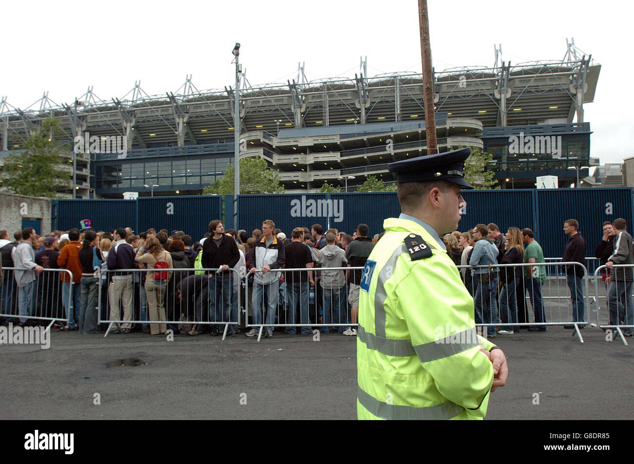 A Garda watches U2 fans queuing at the St James Avenue entrance to Croke Park stadium. Stock Photo
