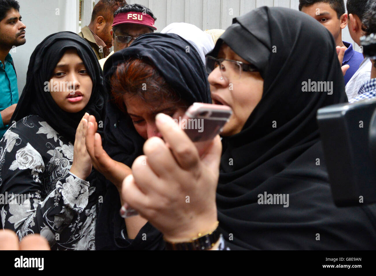 Relatives of a hostage seeking news of their loved one are seen walking away from an upscale restaurant in the Bangladeshi capital Dhaka on July 2, 2016, following a bloody siege there by armed attackers that began on July 1. Heavily armed militants murdered 20 hostages in Bangladesh, hacking many of their victims to death, before six of the attackers were gunned down at the end of a siege July 2 at a restaurant packed with foreigners. As the Islamic State (IS) group claimed responsibility for the carnage at the start of the Eid holiday, Prime Minister Sheikh Hasina said she was determined to Stock Photo