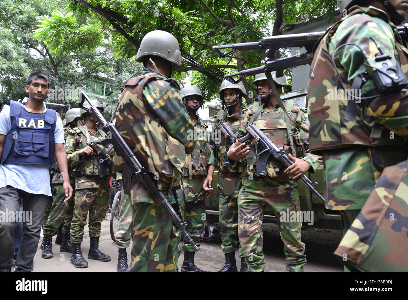 Bangladeshi soldiers and police walk along a street leading to an upscale restaurant in Dhaka on July 2, 2016, following a bloody siege there by armed attackers that began on July 1. Heavily armed militants murdered 20 hostages in Bangladesh, hacking many of their victims to death, before six of the attackers were gunned down at the end of a siege July 2 at a restaurant packed with foreigners. As the Islamic State (IS) group claimed responsibility for the carnage at the start of the Eid holiday, Prime Minister Sheikh Hasina said she was determined to eradicate militancy in the mainly Muslim na Stock Photo