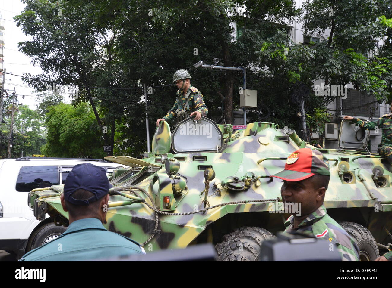 Bangladeshi armored military tank makes its way past journalists, onlookers and police near an upscale restaurant in Dhaka on July 2, 2016, following a bloody siege by armed attackers that began on July 1. Heavily armed militants murdered 20 hostages in Bangladesh, hacking many of their victims to death, before six of the attackers were gunned down at the end of a siege July 2 at a restaurant packed with foreigners. As the Islamic State (IS) group claimed responsibility for the carnage at the start of the Eid holiday, Prime Minister Sheikh Hasina said she was determined to eradicate militancy Stock Photo