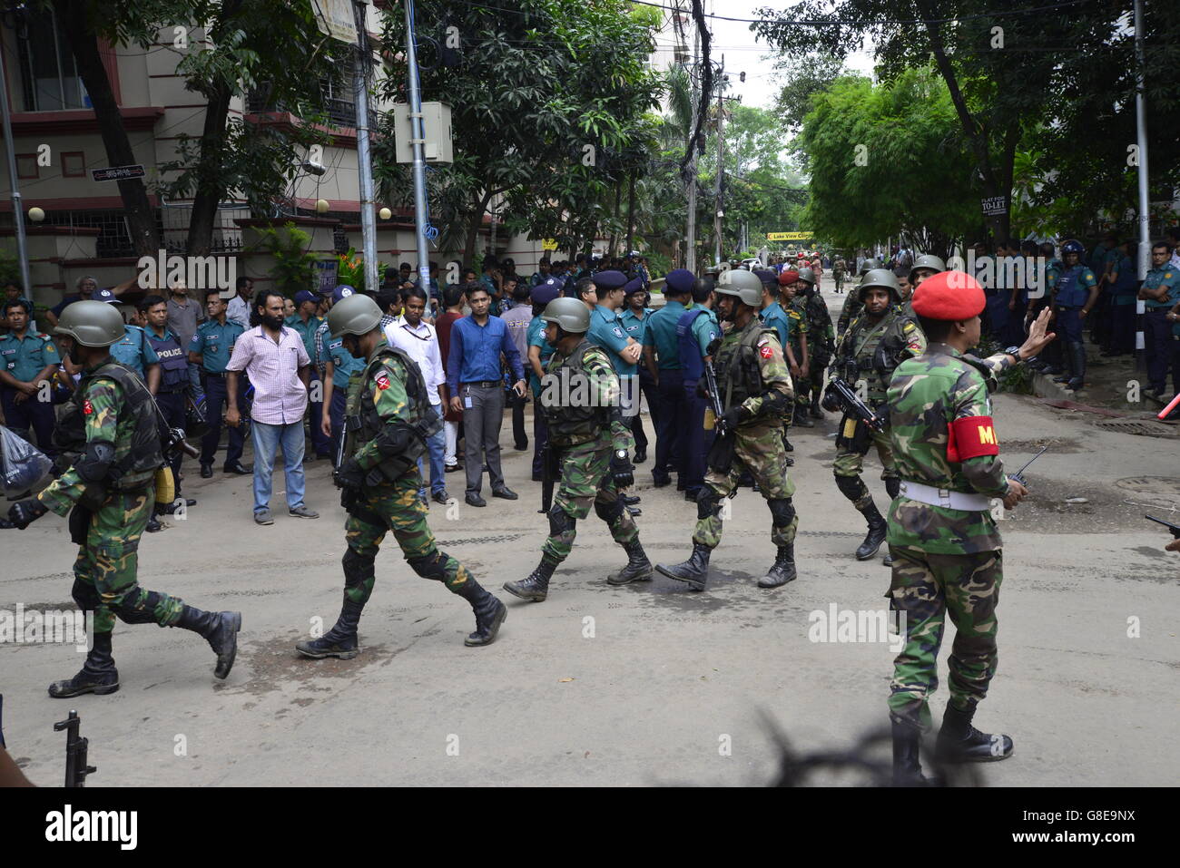 Bangladeshi soldiers and police walk along a street leading to an upscale restaurant in Dhaka on July 2, 2016, following a bloody siege there by armed attackers that began on July 1. Heavily armed militants murdered 20 hostages in Bangladesh, hacking many of their victims to death, before six of the attackers were gunned down at the end of a siege July 2 at a restaurant packed with foreigners. As the Islamic State (IS) group claimed responsibility for the carnage at the start of the Eid holiday, Prime Minister Sheikh Hasina said she was determined to eradicate militancy in the mainly Muslim na Stock Photo