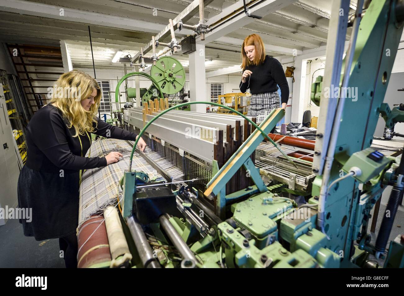 Director of Design and Production Laylah Cook, 24, left, checks cloth on a test run as she and colleague Sally Holditch, 21, debug and maintain a 1980's loom, made by Dornier, the same company responsible for the World War II German Light Bomber, the Dornier Do 17, at The Bristol Weaving Mill, the first working cloth mill in Bristol in nearly 100 years. Stock Photo