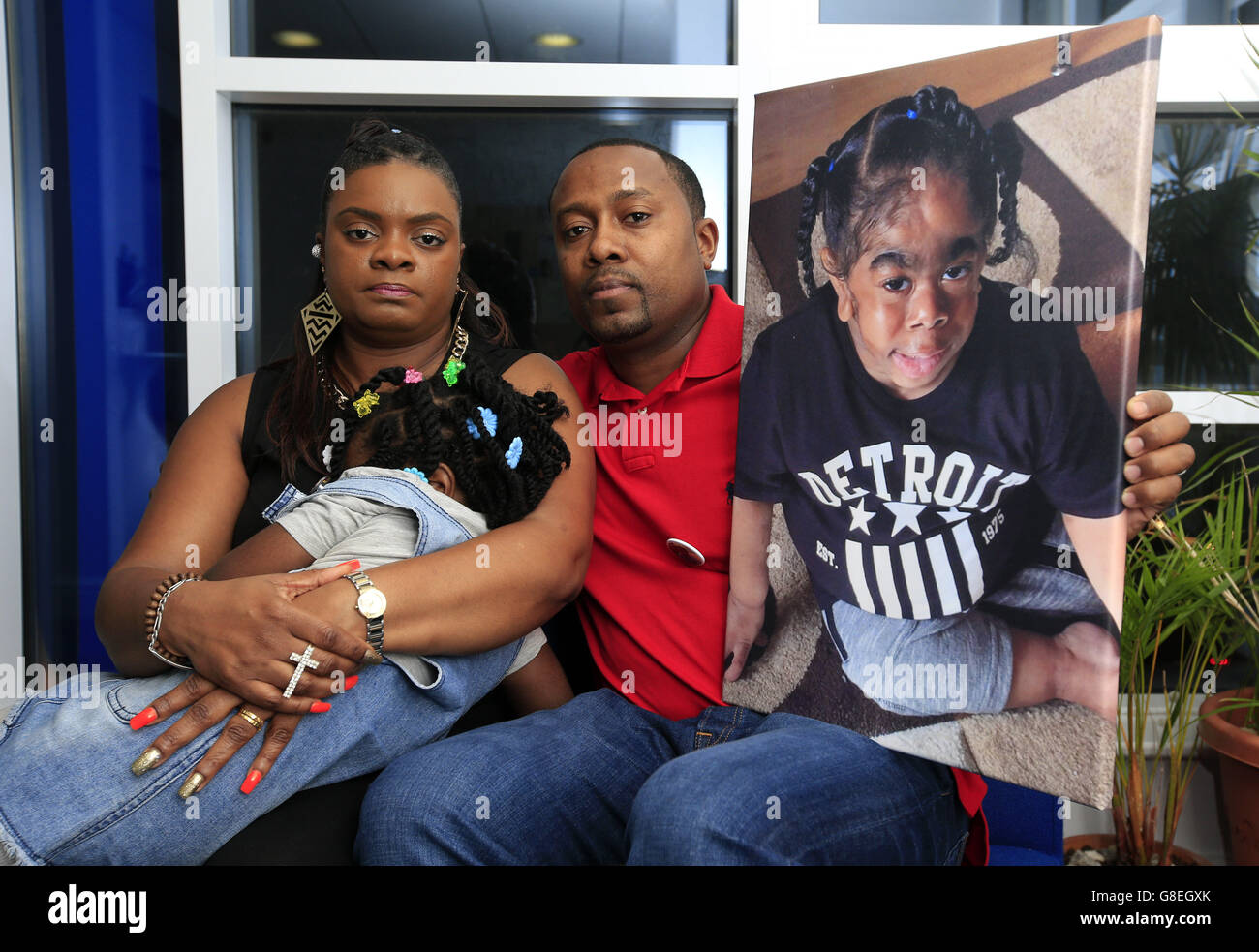 Norris (right) and Pat Martin sit either side of their daughter Tashana-Rae, 5, with an image of their late son TJ, 6, as they are appealing to the public after a laptop containing photos of him was stolen from the Pentecostal City Church, where his funeral service had been held. Stock Photo
