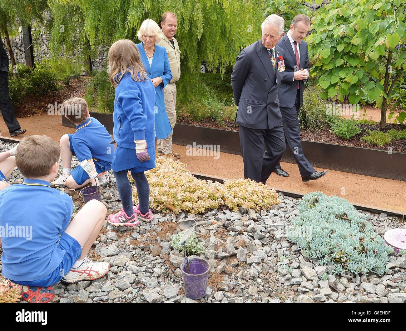 The Prince of Wales and Duchess of Cornwall walk past children working on the flower beds, at the National Arboretum in Canberra the capital of Australia. Stock Photo