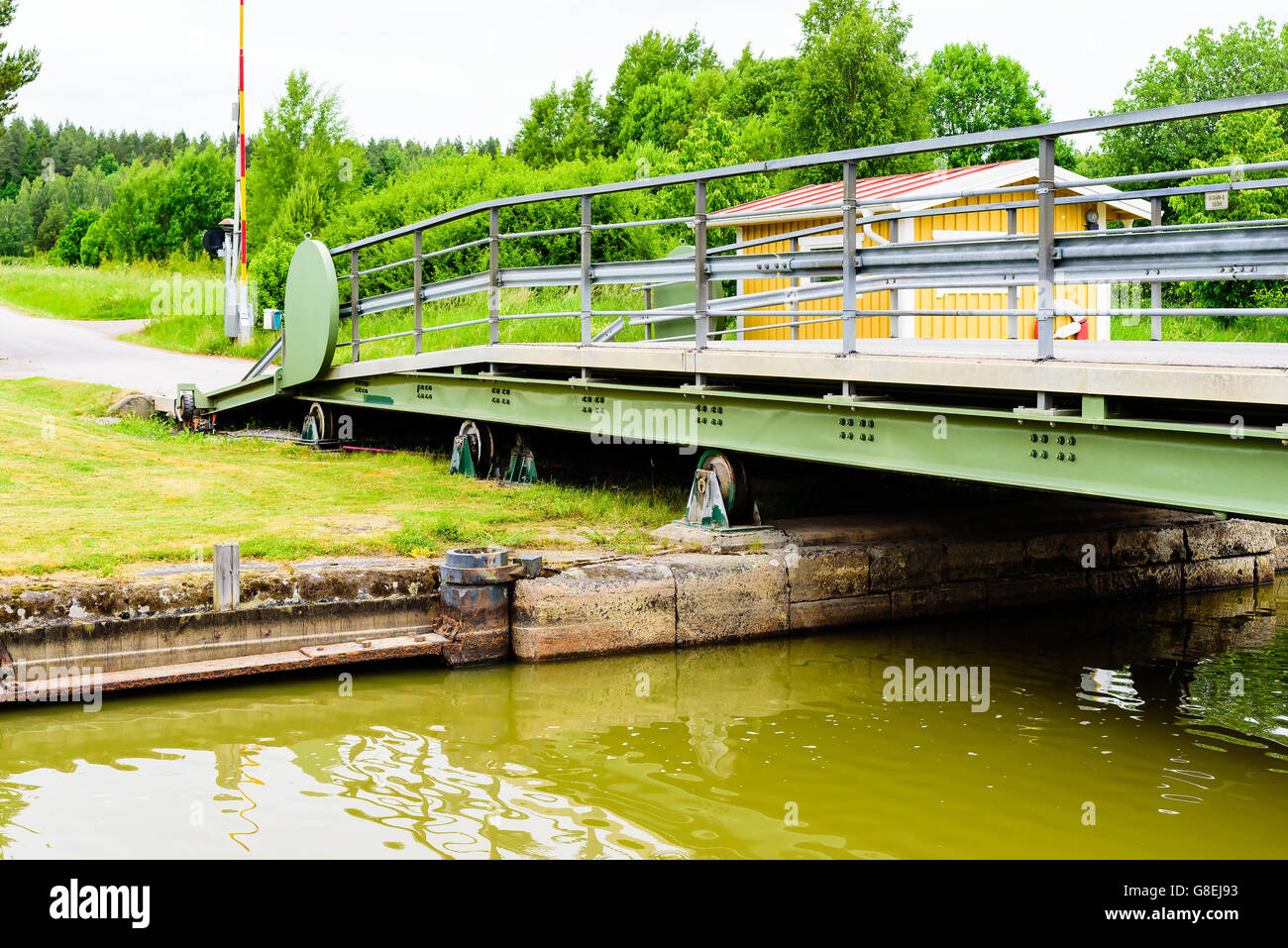 Retractable iron bridge over a canal. Red light signaling boats not to drive through. Bridge is retractable by wheels and rolls Stock Photo
