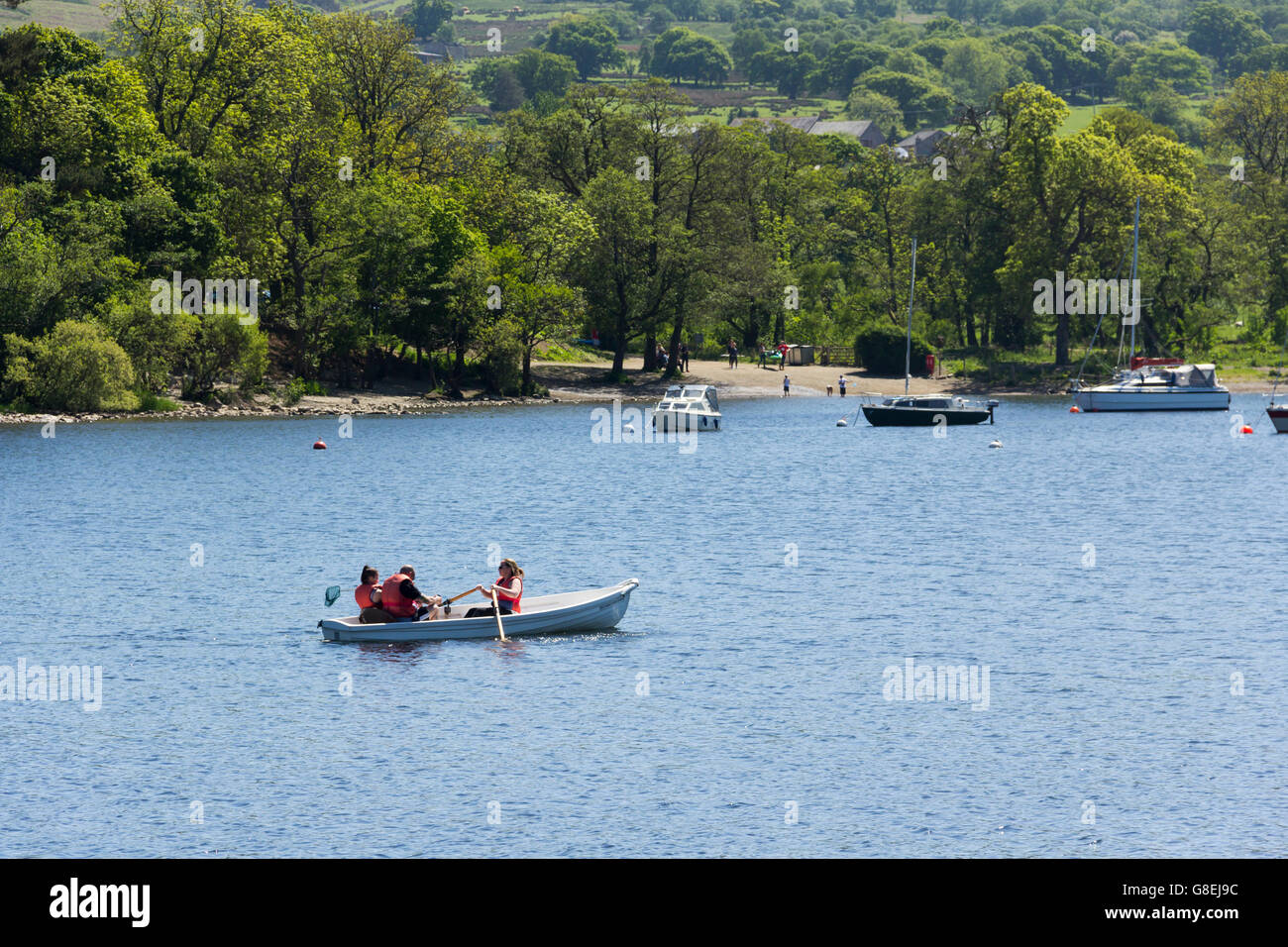 Hire rowing boat, with a group of three people on board, on Ullswater, the second longest lake in the English Lake District Stock Photo