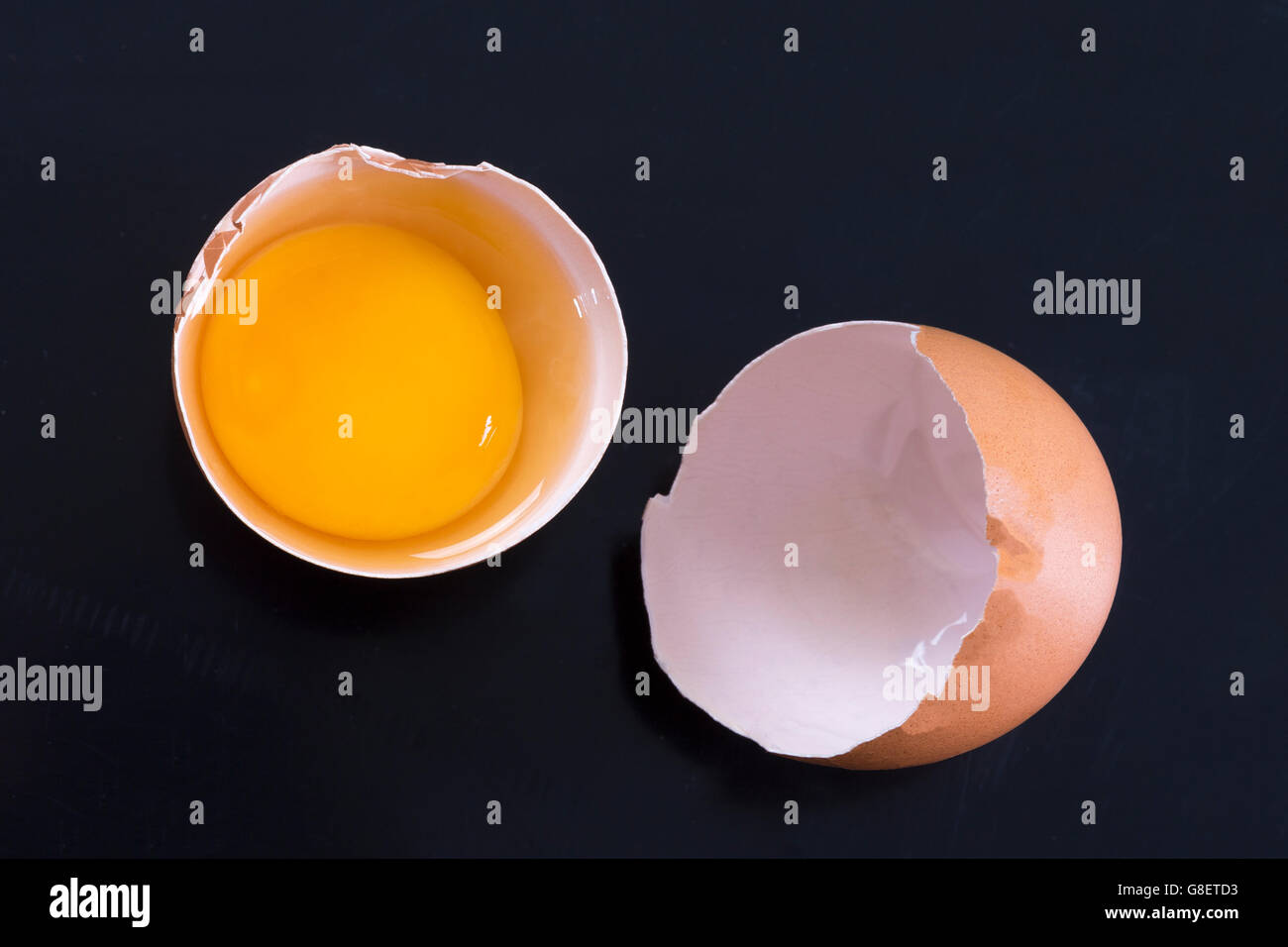Cracked chicken egg on a black background Stock Photo - Alamy