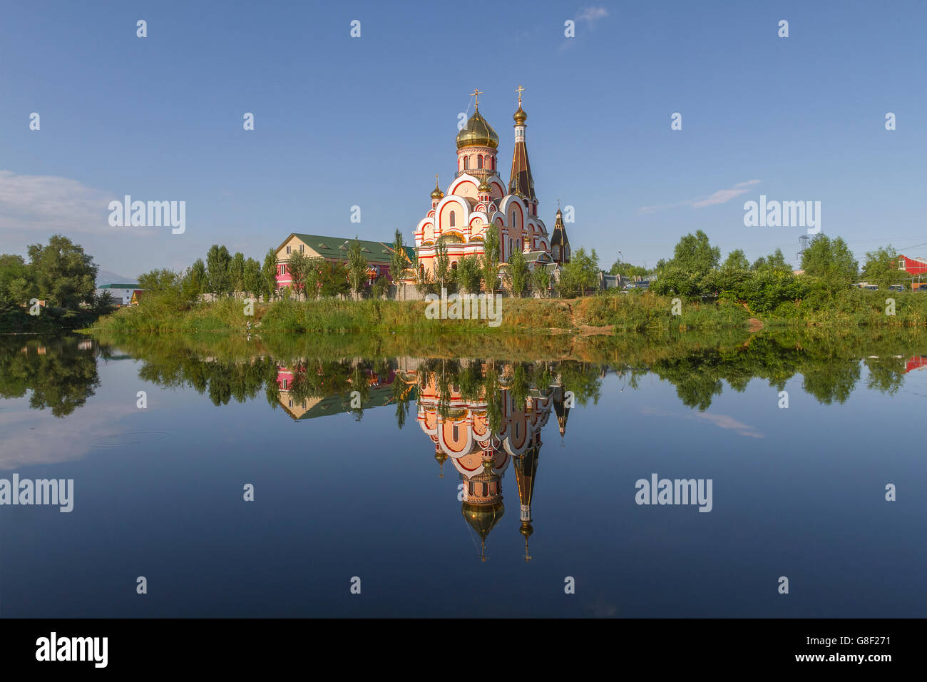 Russian orthodox church in Almaty, Kazakhstan known also as Church of Exaltation of the Holy cross, and its reflection in water. Stock Photo