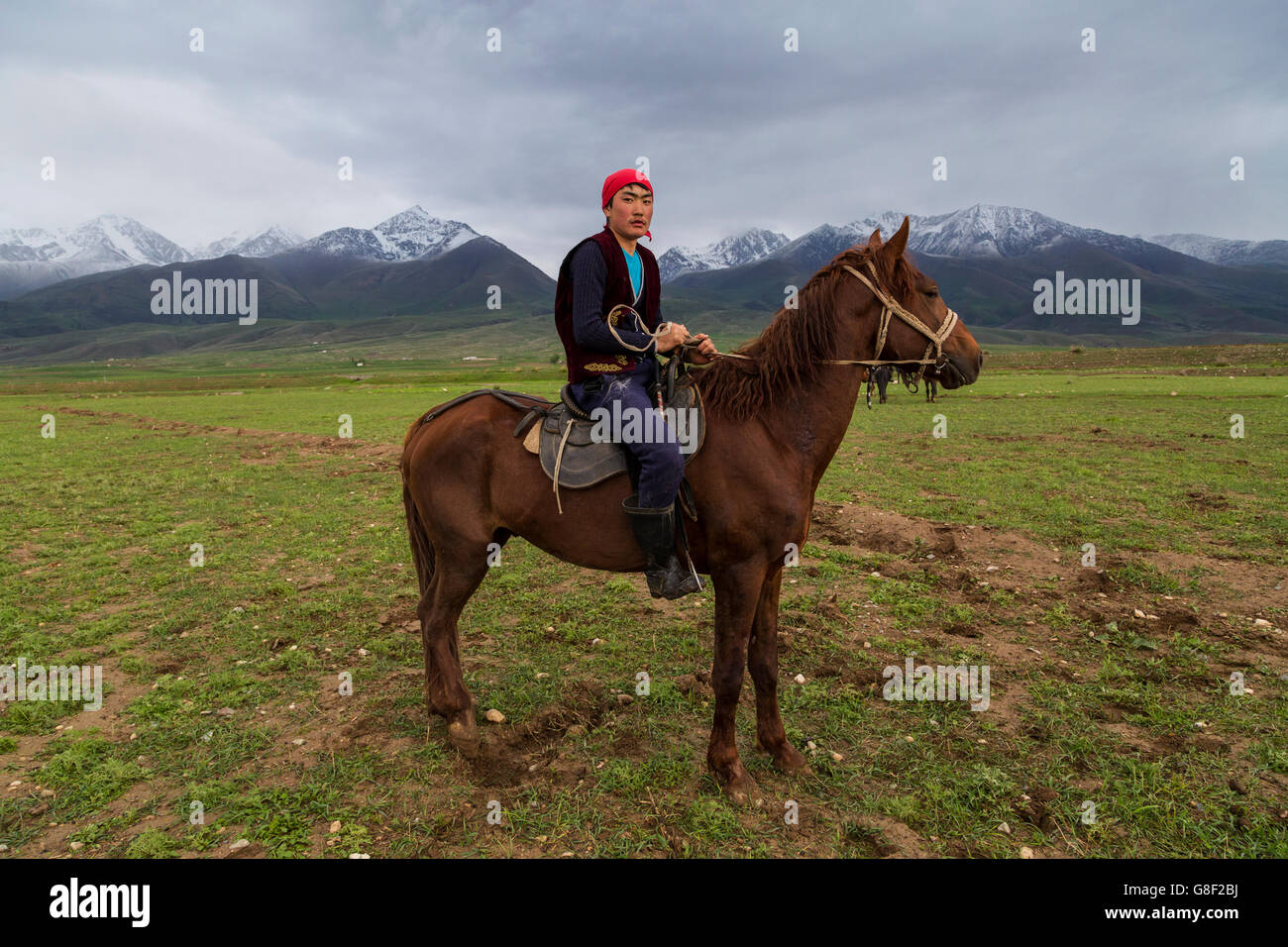 Nomadic horse rider resting on his horse after the traditional nomad games in Issyk Kul Lake, Kyrgyzstan. Stock Photo