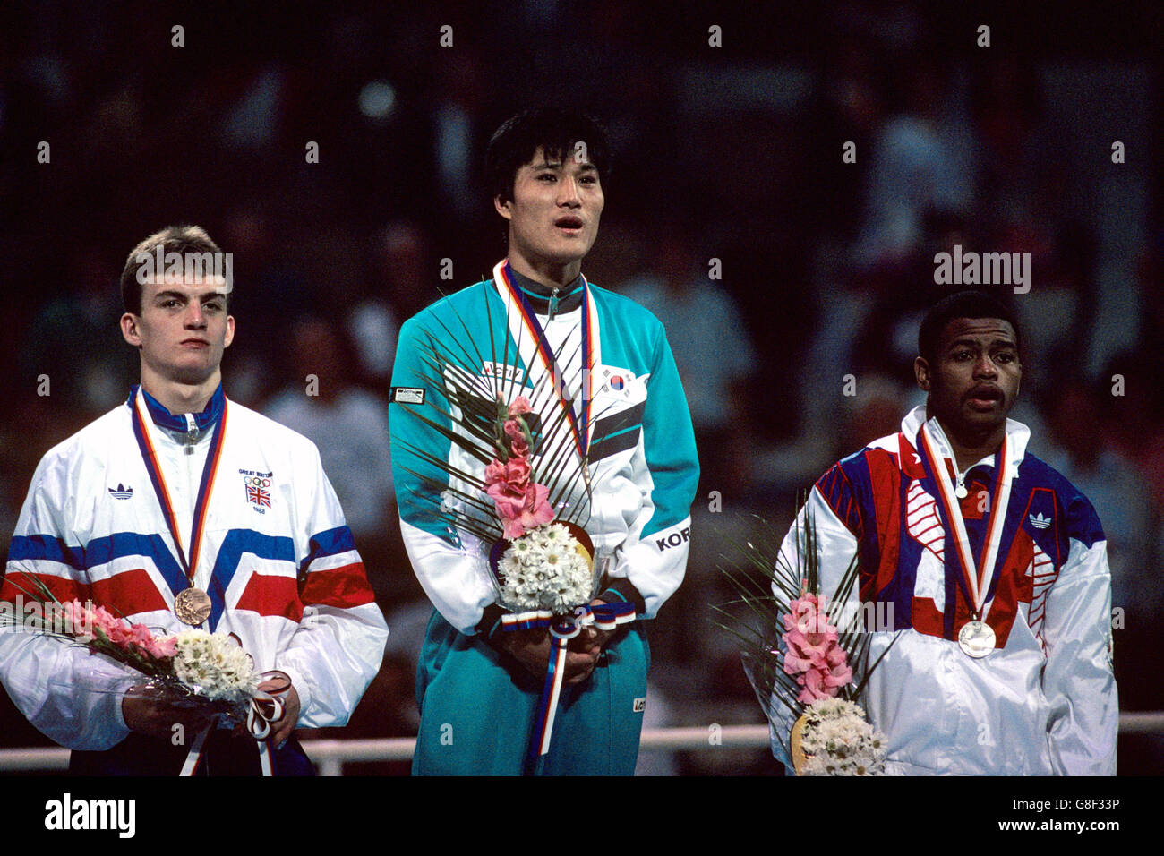 The medallists stand atop the dais as the winner's national anthem is played: (l-r) Great Britain's Richie Woodhall (bronze), Korea's Park Si-Hun (gold), USA's Roy Jones (silver) Stock Photo