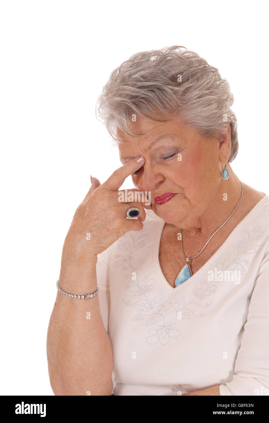 A closeup image of a very sad looking senior citizen woman in her seventies  with short grey hair isolated for white background. Stock Photo