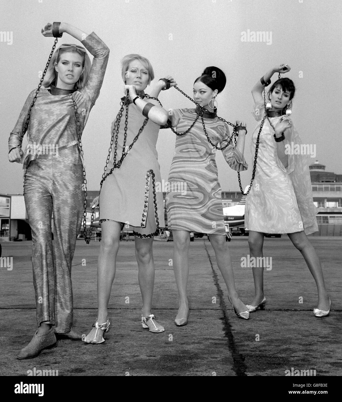 Models 'shackled in chains' at London Airport when they left for the Tunisian markets, where the dresses are to be auctioned. The idea was a sales gimmick by Berkertex, the London Fashion House, to bring notice of their export drive to the North African markets. The models are (l-r) Maureen Walker, Sue Burgess, Marianne Lise and Julia Phillips. Stock Photo