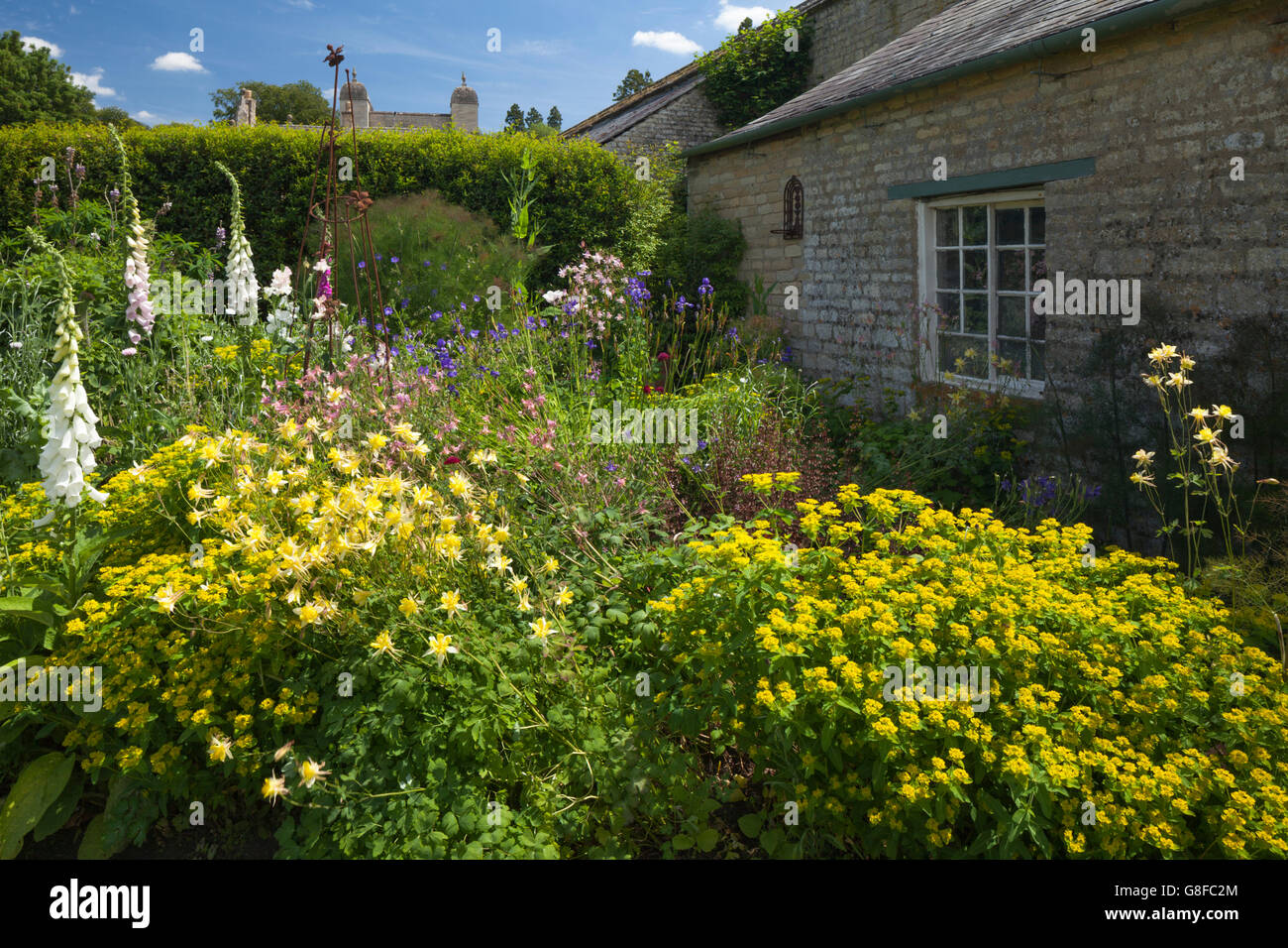 Colourful cottage garden flowers beside a stonebuilt garden store at