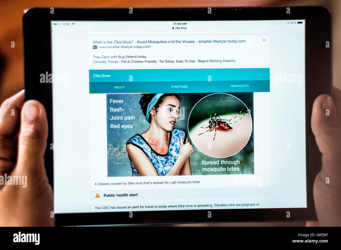 A young woman's hands hold an iPad researching the Zika virus. Closeup. USA. Stock Photo