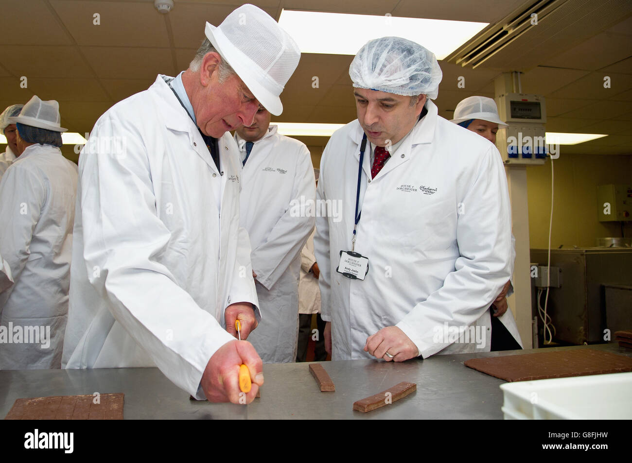 The Prince of Wales cuts chocolates during a tour of The House of
